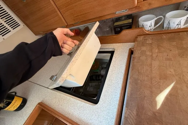 Slide: The Image of Hand opening storage compartment in 2004 Catalina 36 MkII yacht kitchen. - 23