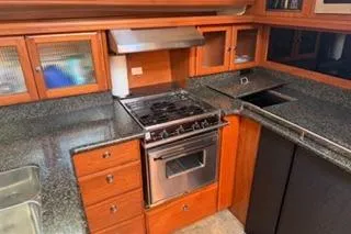Slide: The Image of 2009 Hunter 50 Center Cockpit yacht kitchen with stove, sink, and wooden cabinetry. - 22