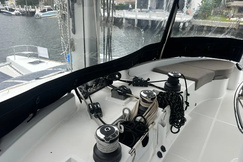 Slide: The Image of Cockpit of 2017 Lagoon 52 F yacht with winches and ropes, docked by the water. - 14