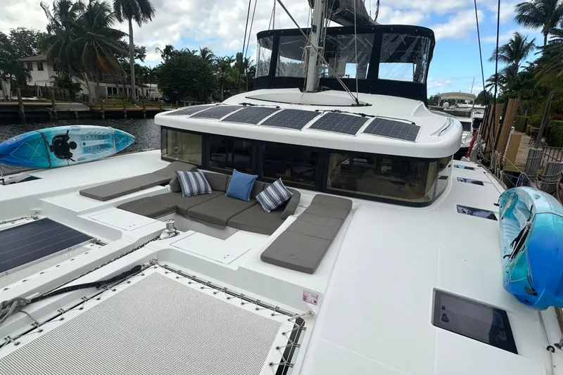 Slide: The Image of 2017 Lagoon 52 F catamaran with solar panels and kayaks, docked near palm trees. - 3