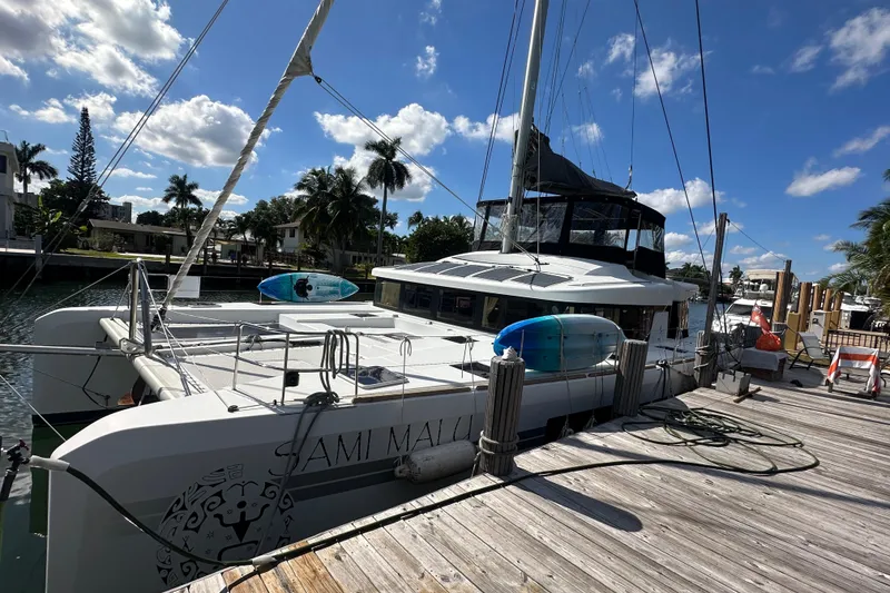 Slide: The Image of 2017 Lagoon 52 F catamaran docked under a sunny sky with palm trees. - 49