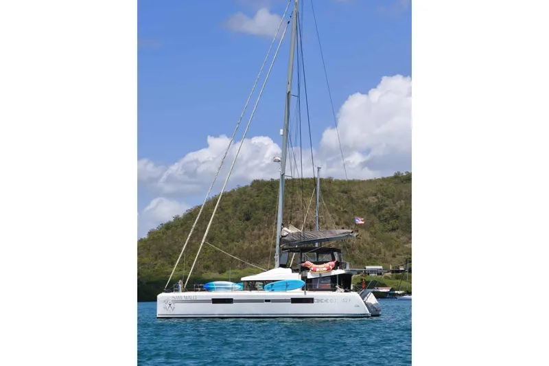 Slide: The Image of 2017 Lagoon 52 F catamaran sailing on blue water near a lush green hillside. - 5