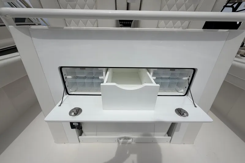 Slide: The Image of 2026 Regulator 28 boat storage compartment with organized tackle boxes and drawer. - 26