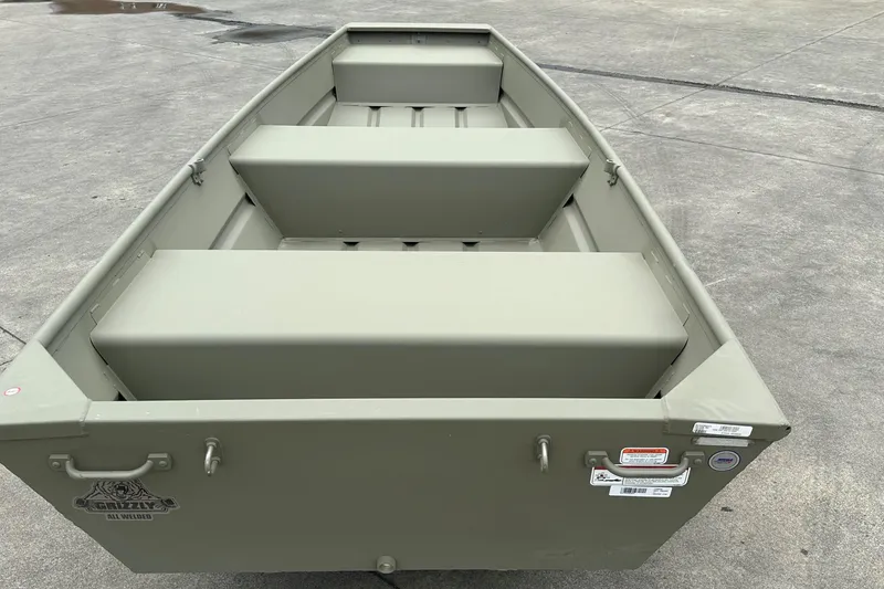 Slide: The Image of 2026 Tracker Grizzly 12 Jon boat on concrete surface, showcasing interior seating and design. - 2