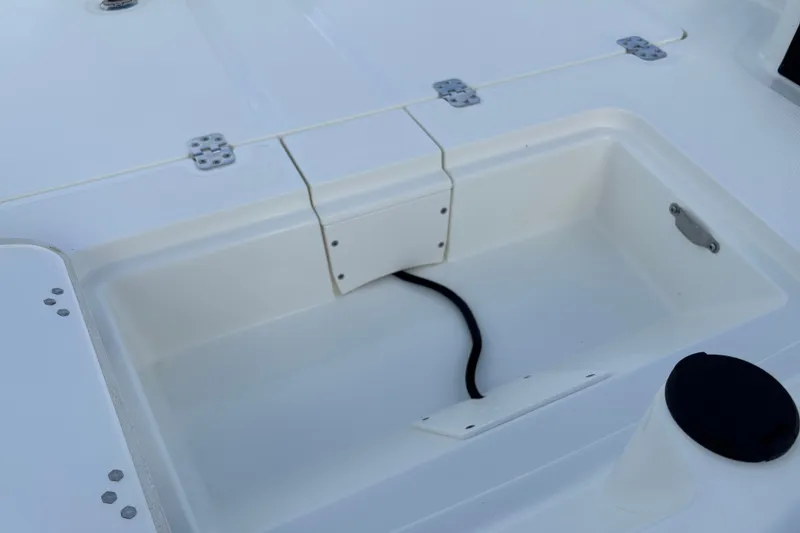 Slide: The Image of 2026 Mako Pro Skiff 15 CC boat storage compartment with hinges and drainage. - 14