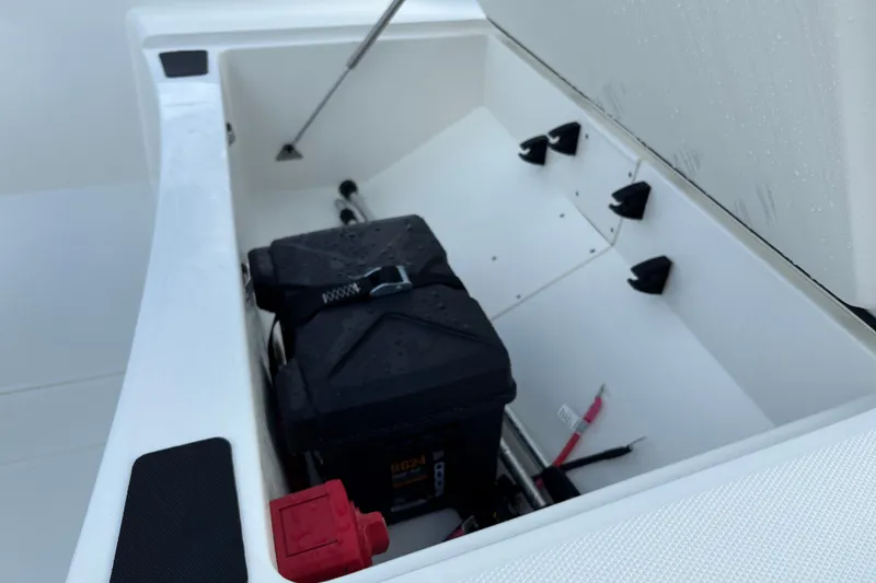 Slide: The Image of Open storage compartment in 2026 Mako Pro Skiff 15 CC boat, featuring battery and accessories. - 15