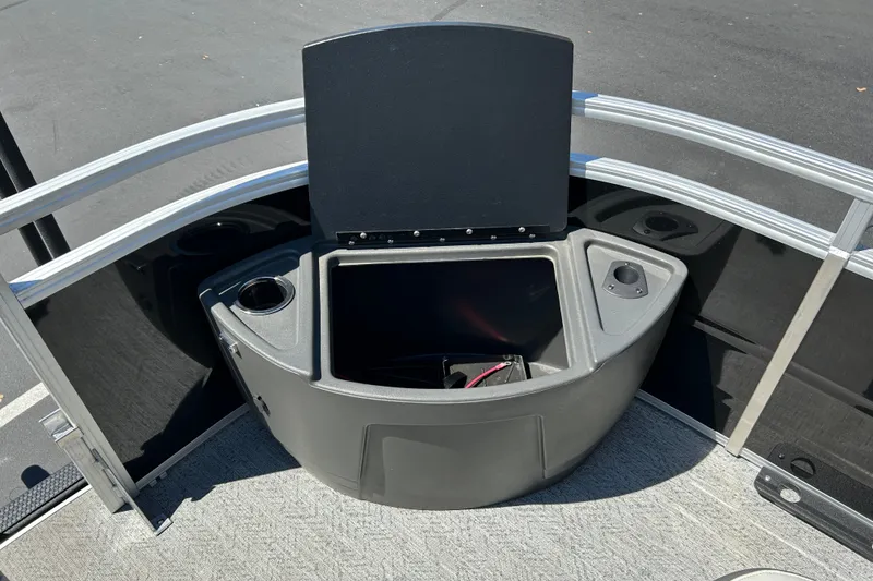 Slide: The Image of 2026 Sun Tracker Fishin' Barge 22 DLX storage compartment with open lid and cup holders. - 13