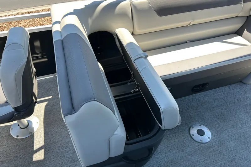 Slide: The Image of Sun Tracker Fishin' Barge 22 DLX 2026 interior seating with storage compartment open. - 18