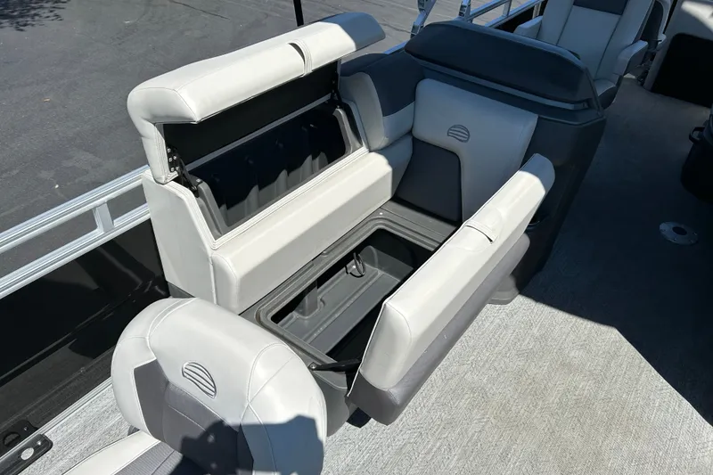 Slide: The Image of 2026 Sun Tracker Fishin' Barge 22 DLX interior seating with storage compartments open. - 15