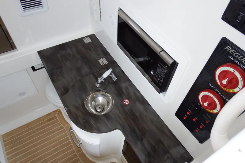 Slide: The Image of 2018 Regulator 34SS boat interior with sink, control panel, and microwave. - 18