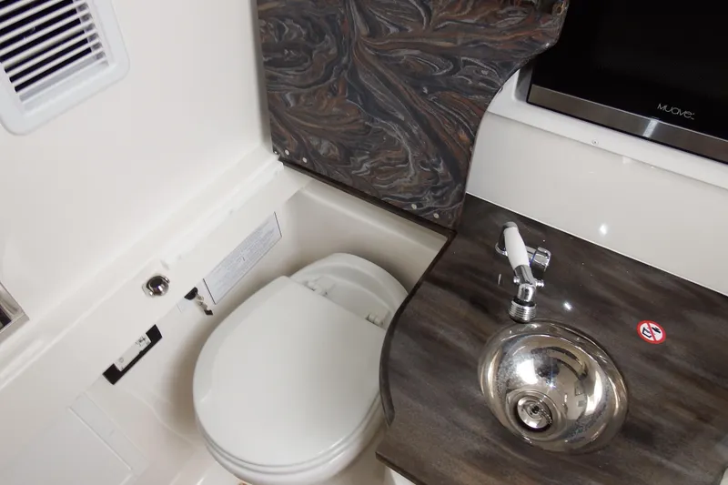 Slide: The Image of 2018 Regulator 34SS boat bathroom with toilet, sink, and marble countertop. - 28