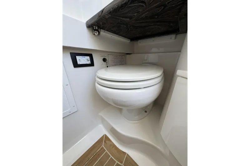 Slide: The Image of 2018 Regulator 34SS boat interior featuring a compact marine toilet setup. - 53