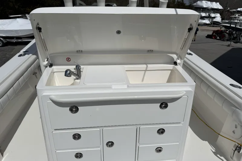 Slide: The Image of 2018 Regulator 34SS boat sink and seating area, featuring dual basins and chrome faucet. - 66