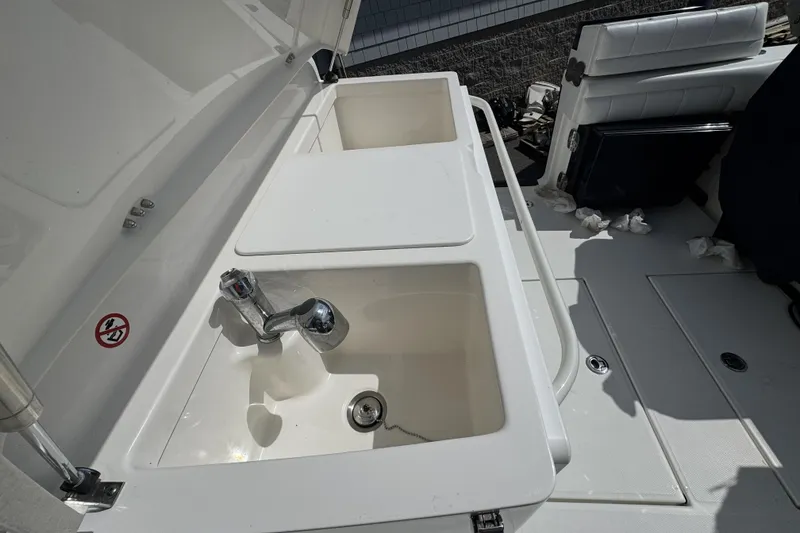 Slide: The Image of 2018 Regulator 34SS boat sink and seating area, featuring dual basins and chrome faucet. - 68