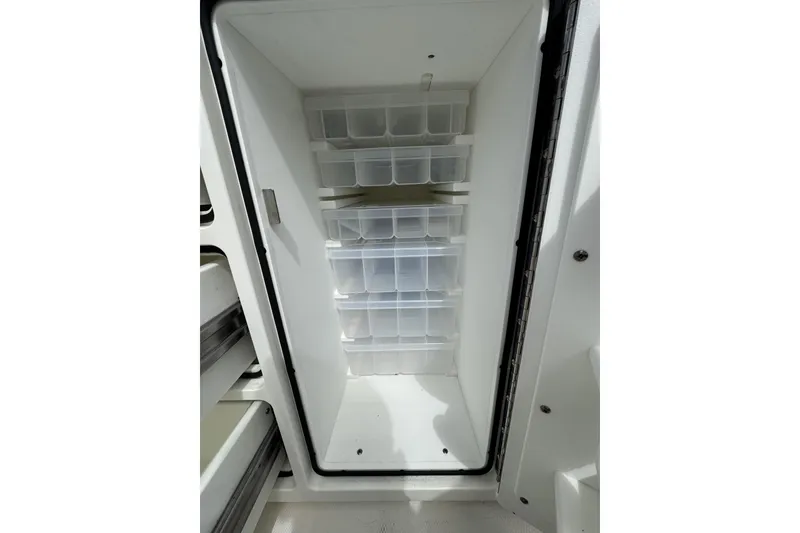 Slide: The Image of Open storage compartment with organized plastic bins in a 2018 Regulator 34SS boat. - 73