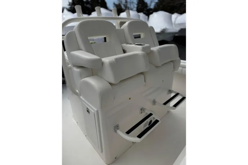 Slide: The Image of 2018 Regulator 34SS boat seating with white cushioned chairs and footrests. - 77