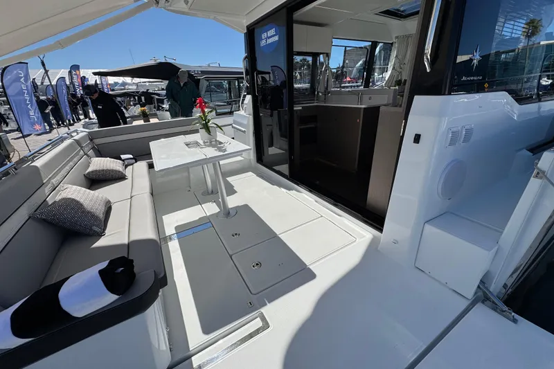 Slide: The Image of 2026 Jeanneau NC 1295 Coupe boat interior with seating and table, docked at marina. - 6