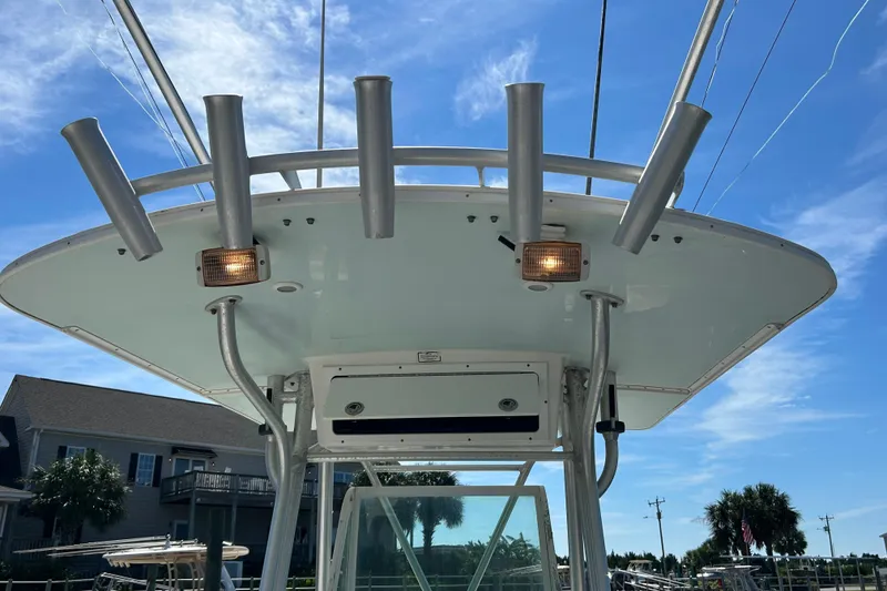 Slide: The Image of 2005 Regulator 26 Forward Seating boat with rod holders and lights under clear blue sky. - 24