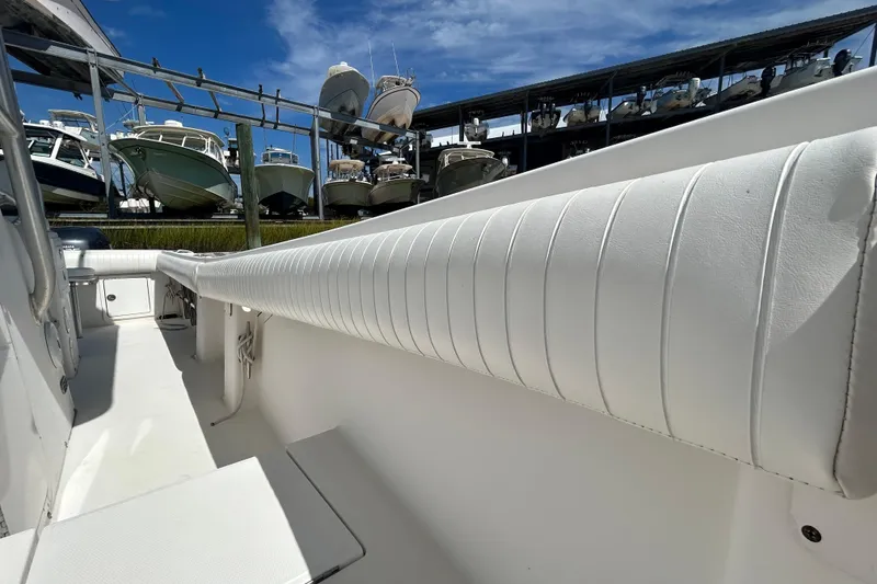 Slide: The Image of 2005 Regulator 26 Forward Seating boat interior with white upholstery and docked boats in background. - 38