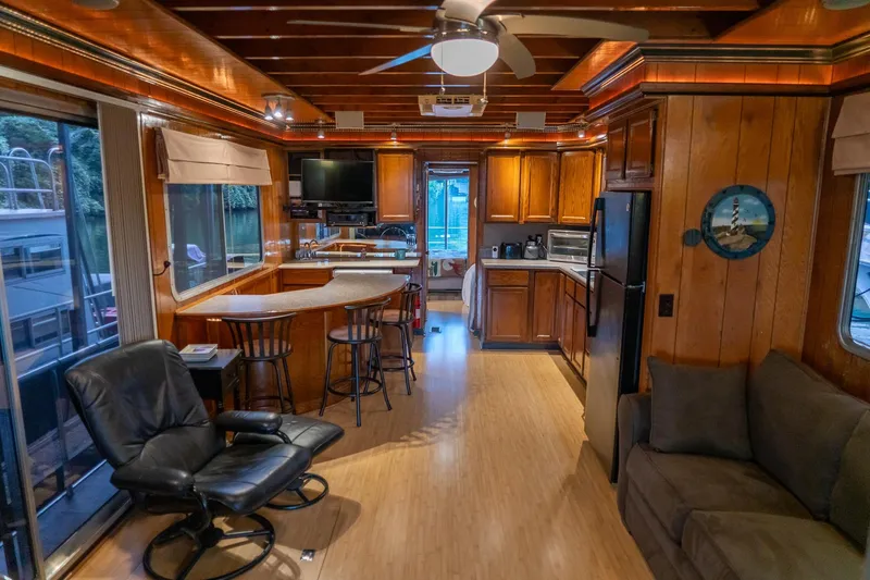 Slide: The Image of 1984 Sumerset 60 X 14 houseboat interior with wood paneling, kitchen, and seating area. - 11