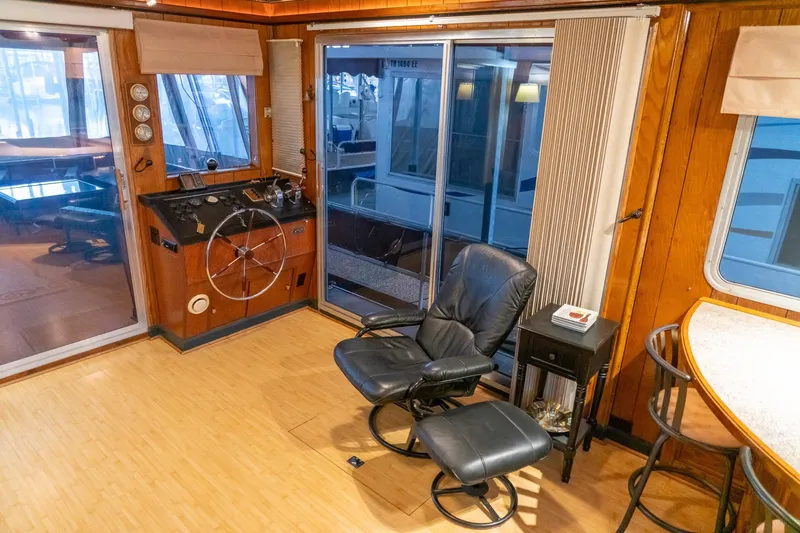 Slide: The Image of 1984 Sumerset 60 X 14 houseboat interior with helm, leather chair, and sliding glass doors. - 13