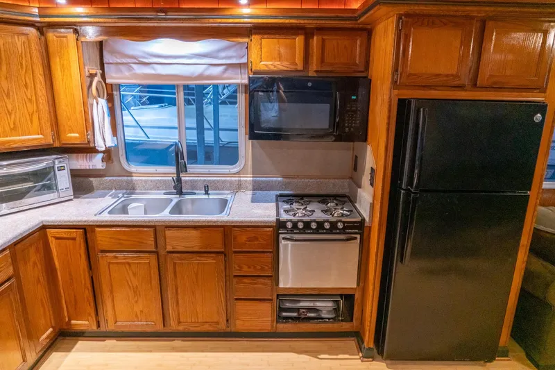 Slide: The Image of 1984 Sumerset 60 X 14 Houseboat kitchen with wooden cabinets and modern appliances. - 18