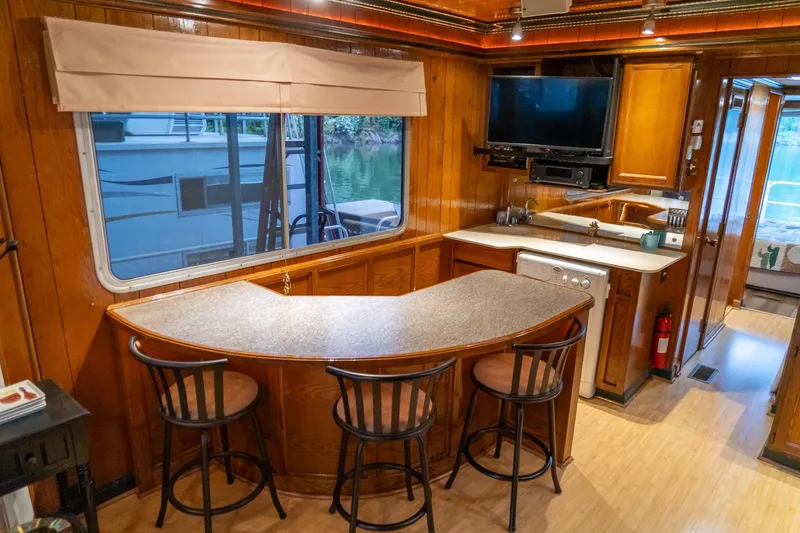 Slide: The Image of 1984 Sumerset 60 X 14 houseboat interior with kitchen, bar seating, and window view. - 21