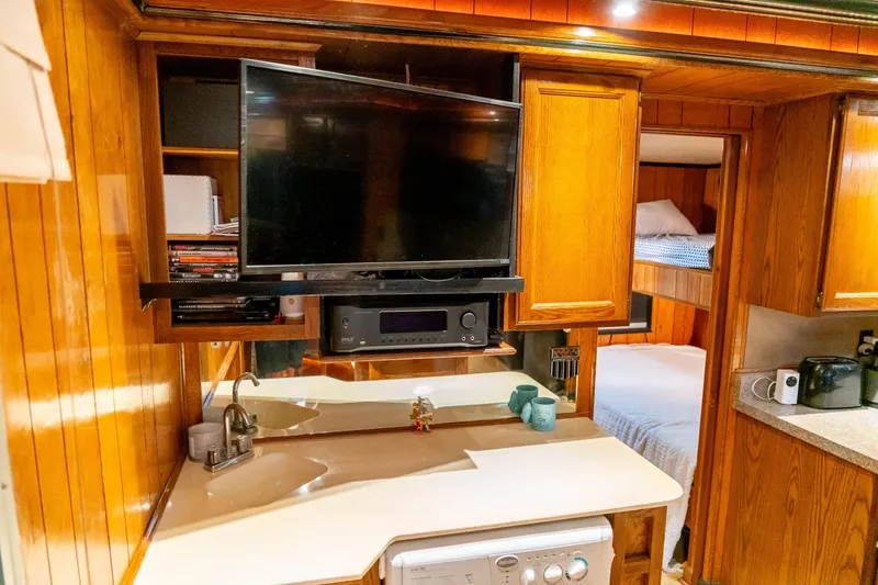 Slide: The Image of 1984 Sumerset 60 X 14 houseboat interior with TV, sink, and wooden cabinetry. - 24