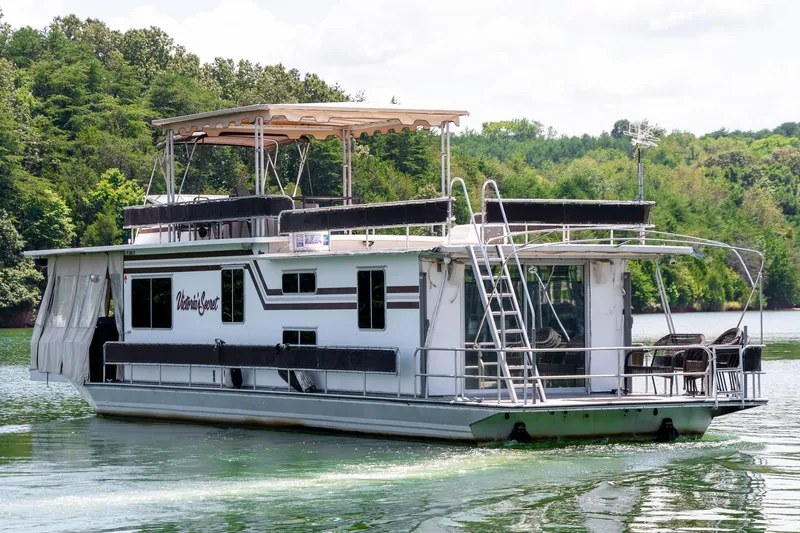 Slide: The Image of 1984 Sumerset 60 X 14 houseboat on a serene lake with lush green surroundings. - 3