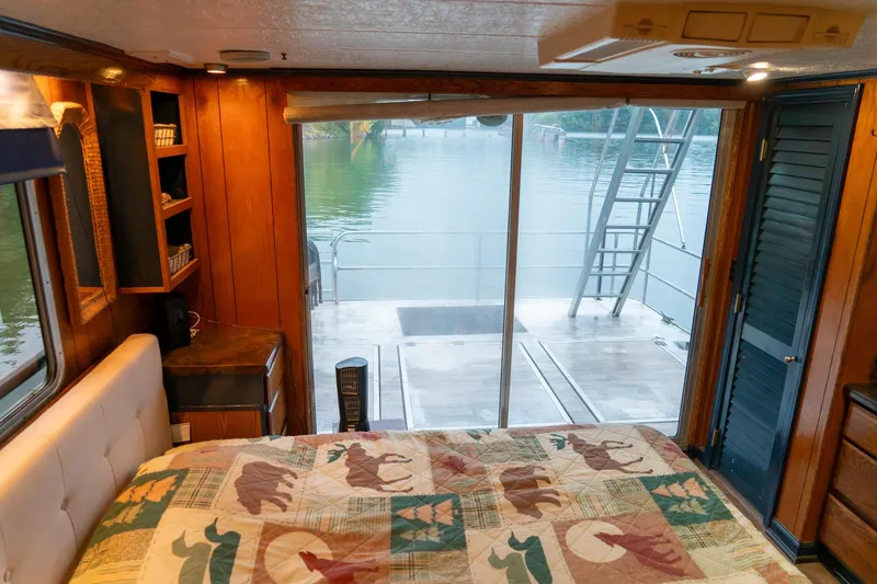 Slide: The Image of 1984 Sumerset 60 X 14 houseboat bedroom with lake view, wooden interior, and sliding glass doors. - 34