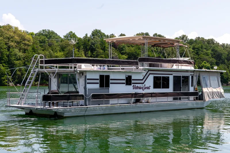Slide: The Image of 1984 Sumerset 60 X 14 houseboat on a serene lake with lush green trees. - 6