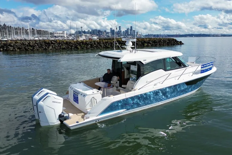 The Image of 2026 Tiara Yachts 43 LE cruising near city skyline, featuring twin Mercury engines. - 0
