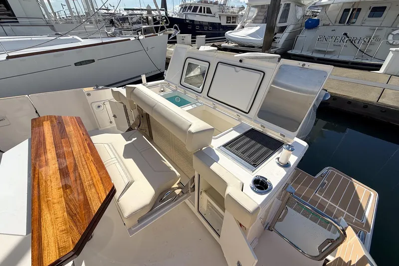 Slide: The Image of 2026 Tiara Yachts 43 LE cockpit with seating, grill, and wooden table at marina. - 25