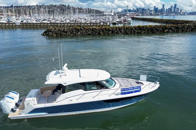 Slide: The Image of 2026 Tiara Yachts 43 LE cruising near marina with city skyline in background. - 3