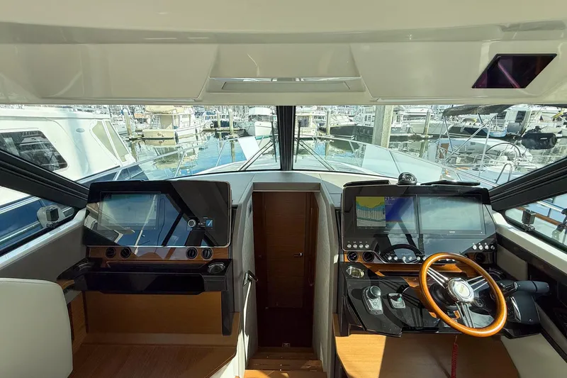 Slide: The Image of 2026 Tiara Yachts 43 LE helm with dual screens and wooden steering wheel. - 39