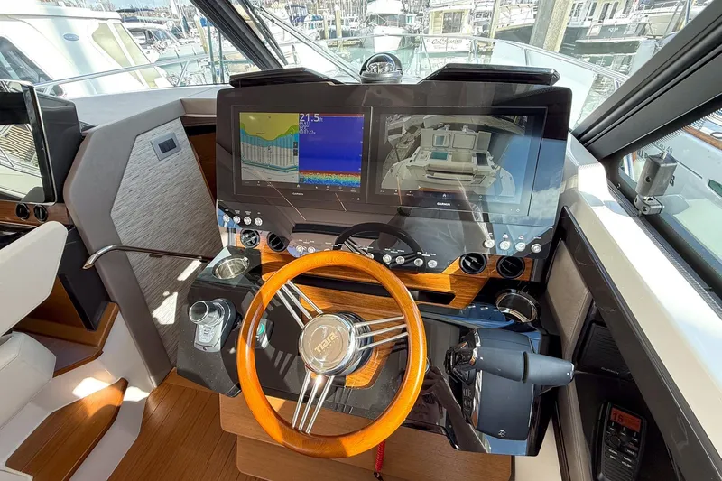 Slide: The Image of Helm of 2026 Tiara Yachts 43 LE with advanced navigation displays and wooden steering wheel. - 43