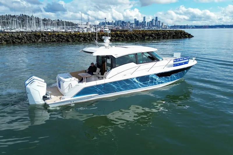 Slide: The Image of 2026 Tiara Yachts 43 LE cruising near a marina with city skyline backdrop. - 7