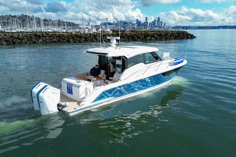 Slide: The Image of 2026 Tiara Yachts 43 LE cruising near a marina with city skyline in background. - 8