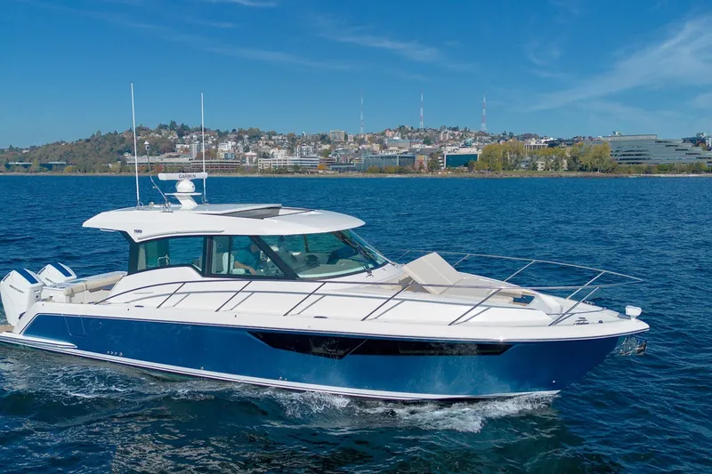The Image of 2026 Tiara Yachts 43 LE cruising on a scenic blue lake with city skyline backdrop. - 0