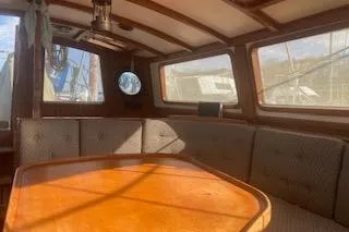 Slide: The Image of 1985 Baba 40 Pilot House interior with wooden finish, steering wheel, and seating area. - 2