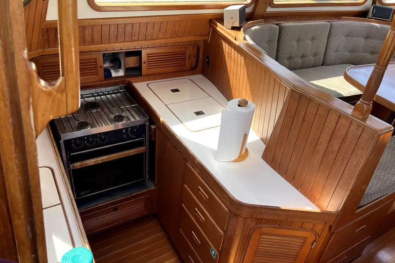 Slide: The Image of 1985 Baba 40 Pilot House interior with wooden cabinetry and compact kitchen area. - 29