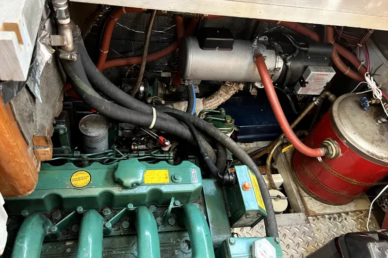 Slide: The Image of Engine compartment of a 1985 Baba 40 Pilot House sailboat, showcasing mechanical components and hoses. - 42