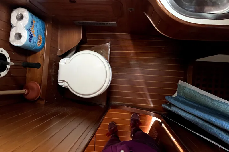 Slide: The Image of Wooden boat bathroom with toilet, plunger, and paper towels, Baba 40 Pilot House, 1985. - 54