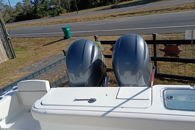 Slide: The Image of 2021 Sea Hunt Gamefish 27 Coffin Box with dual outboard motors, parked near a road. - 33