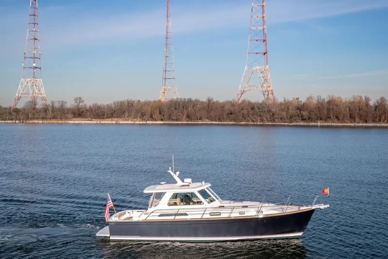 The Image of 2009 Sabre 42 Hard Top Express yacht cruising on a calm river with radio towers in the background. - 1