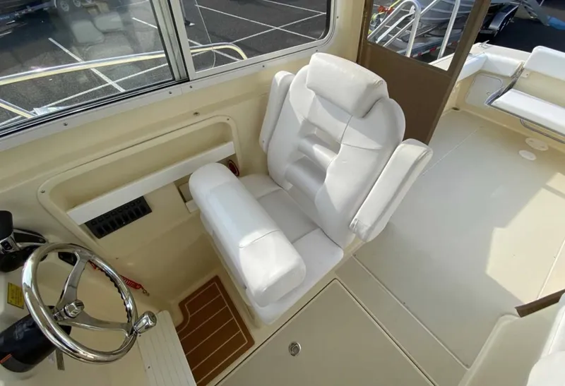 Slide: The Image of 2024 NorthCoast 235 HT boat interior with white captain's chair and steering wheel. - 7
