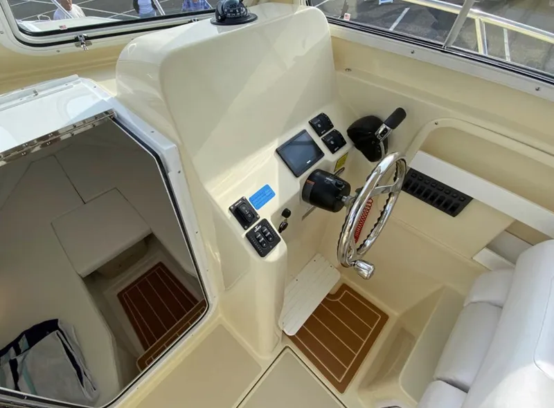 Slide: The Image of 2024 NorthCoast 235 HT boat interior with helm, steering wheel, and cabin entrance. - 8