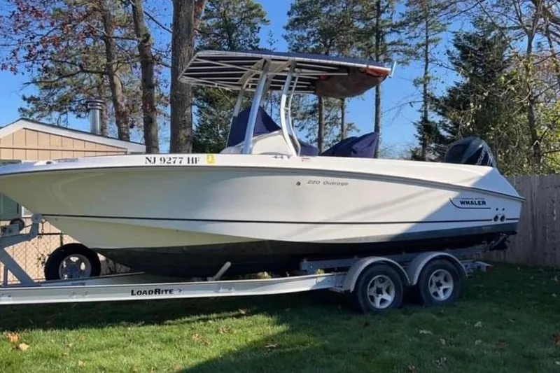 The Image of 2013 Boston Whaler 220 Outrage boat on trailer, parked outdoors. - 0