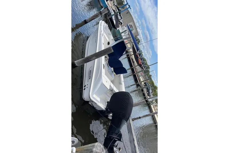 Slide: The Image of 2013 Boston Whaler 220 Outrage docked at marina, rear view. - 4