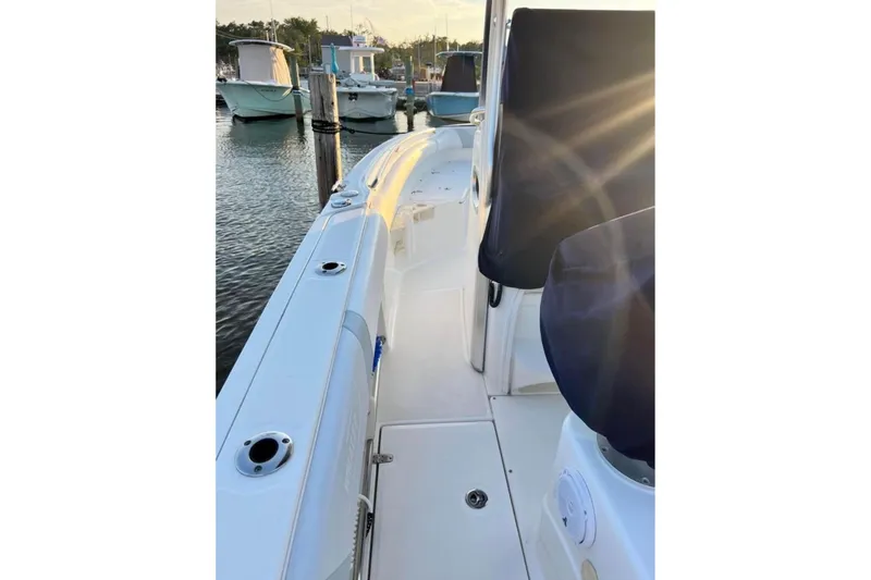 Slide: The Image of 2013 Boston Whaler 220 Outrage boat docked at marina, sunlit deck view. - 5